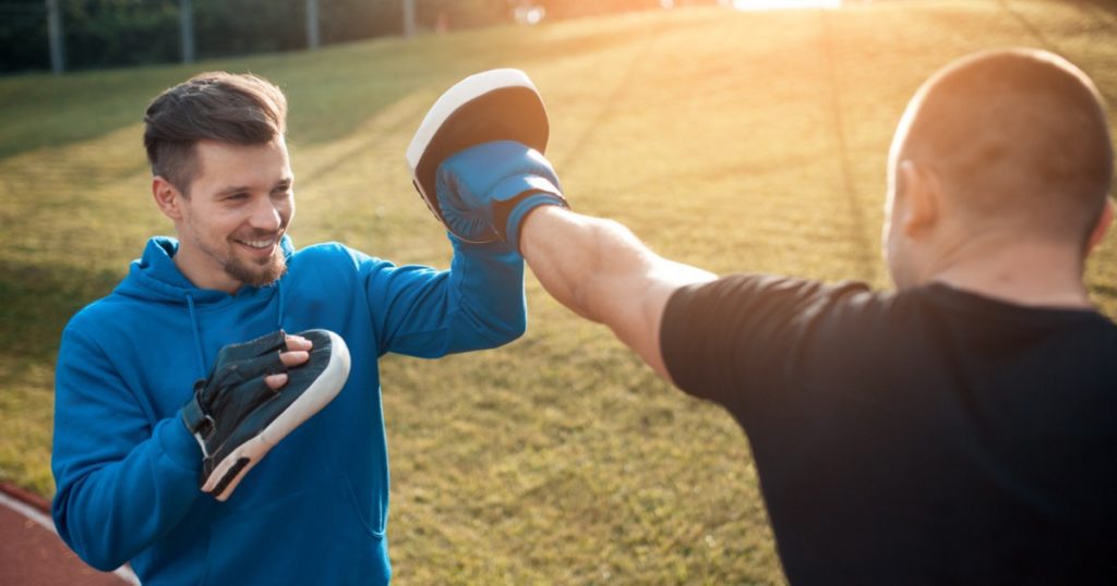 Closeup of two men boxing on a field.