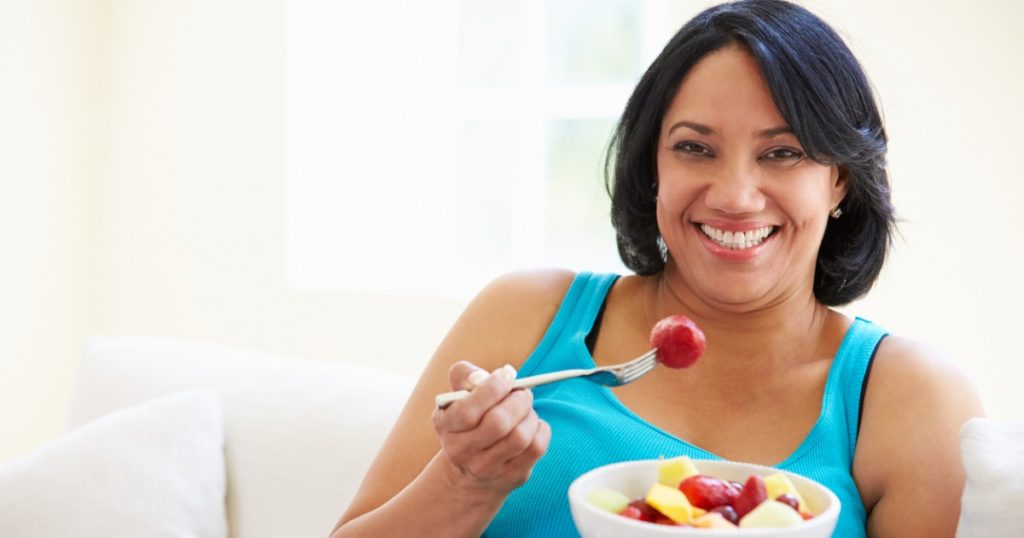 Woman eating a bowl of fruits.