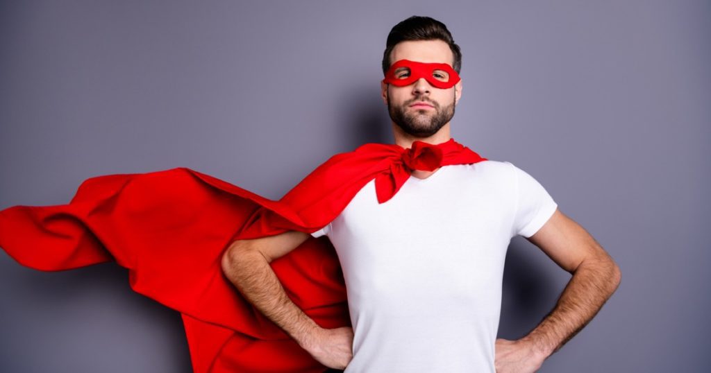 Person standing with hands on hips, wearing a red cape and red eye mask.