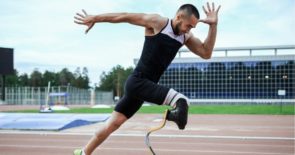 Male athlete with a prosthetic leg in an explosive running position on an outdoor running track.