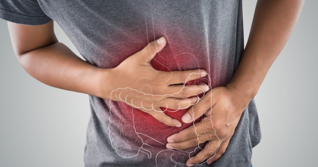 Closeup of a person gripping their stomach with the outline of the intestines in a red circle.